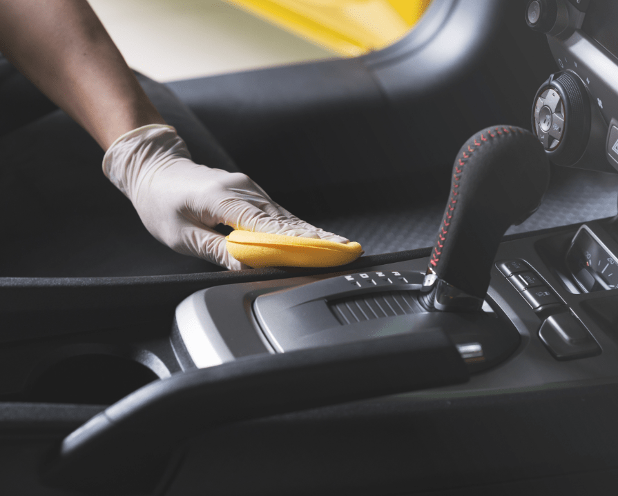 Hand with glove cleaning down the interior of a car
