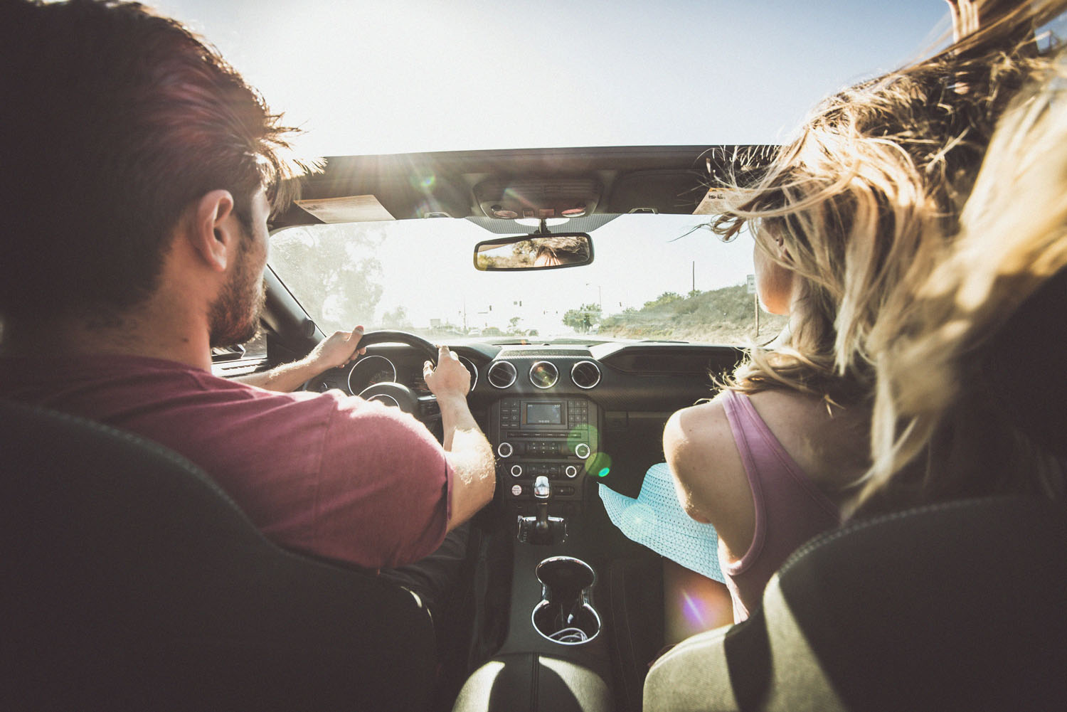 Couple on the open road with the sun shining and the car's top down